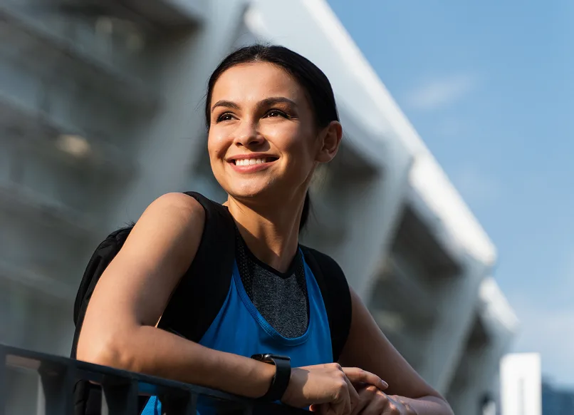 Woman smiling outdoors in front of a modern medical building